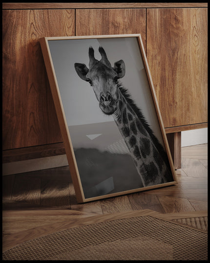 Ein gerahmtes Poster vom Kopf einer Giraffe in schwarz-weiß, an einer Holzkommode angelehnt und stehend auf dem Holzboden