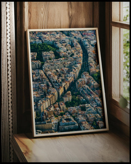 Ein gerahmtes Poster von einer langen Straße die durch die Innenstadt von Barcelona führt, vor einem Fenster an die Wand angelehnt