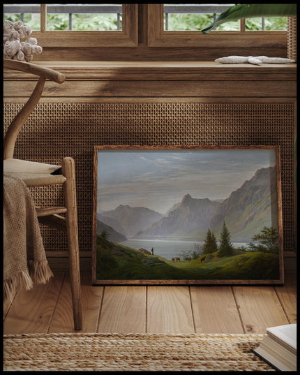 Ein gerahmter Kunstdruck von einer steilen Berglandschaft mit einem Gebirgssee am Morgen, vor einem Fenster an die Wand angelehnt